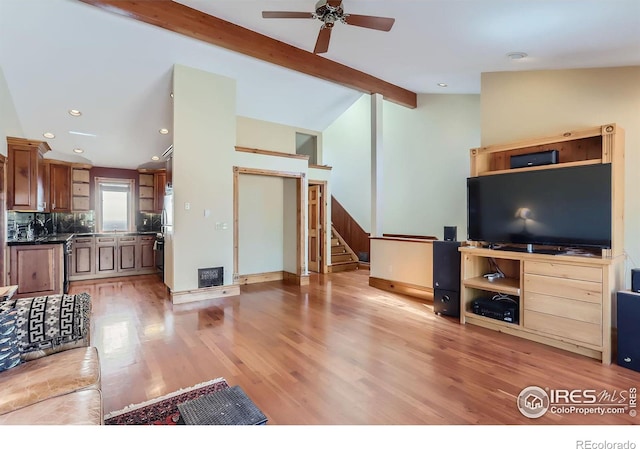 living room featuring vaulted ceiling with beams, light hardwood / wood-style flooring, and ceiling fan