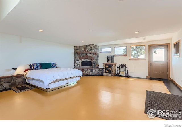 bedroom with concrete flooring and a stone fireplace