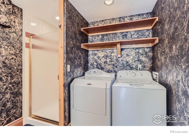 laundry area featuring washing machine and clothes dryer and a textured ceiling