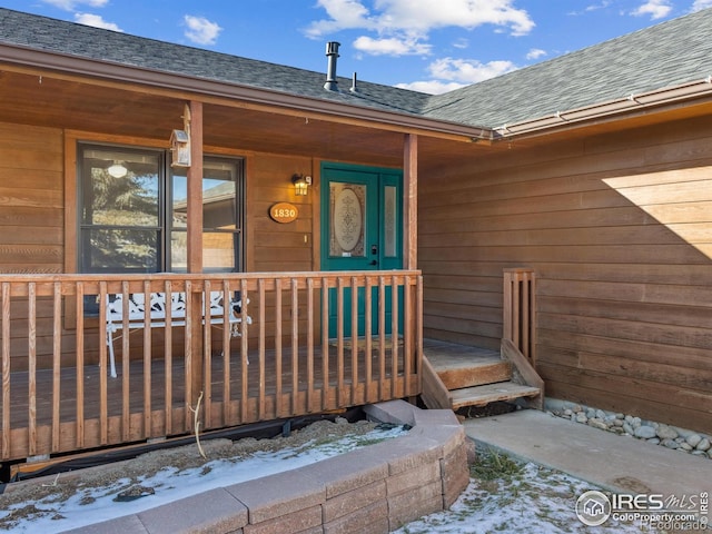 snow covered property entrance with covered porch