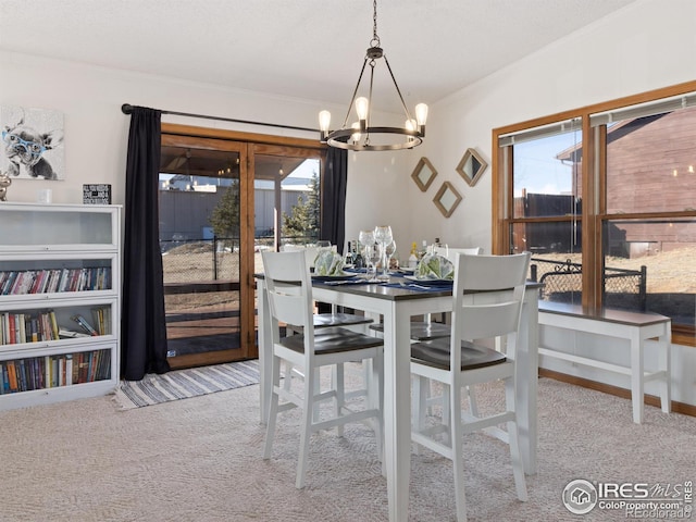 carpeted dining room featuring crown molding and an inviting chandelier