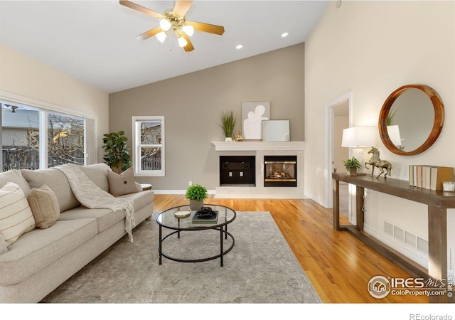 living room featuring light hardwood / wood-style flooring, high vaulted ceiling, and ceiling fan