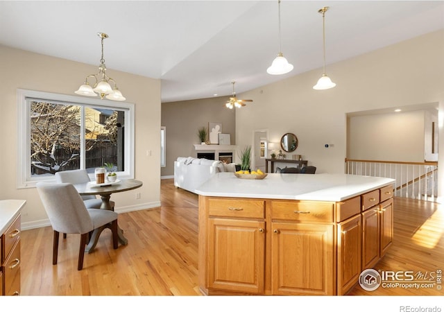 kitchen featuring an inviting chandelier, a center island, vaulted ceiling, hanging light fixtures, and light hardwood / wood-style flooring