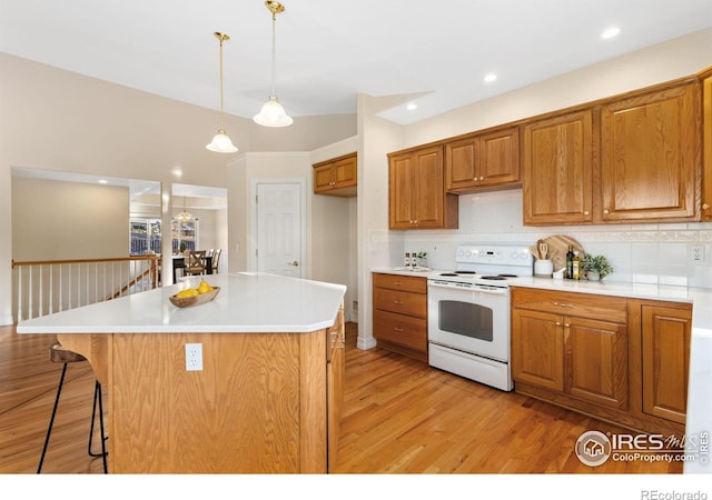 kitchen featuring a breakfast bar area, hanging light fixtures, a center island, light hardwood / wood-style floors, and white electric stove