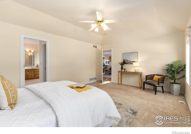 bedroom featuring ceiling fan, ensuite bath, vaulted ceiling, and light carpet