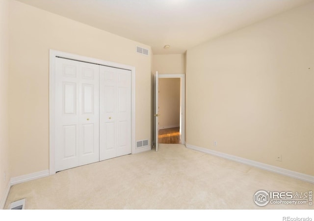 unfurnished bedroom with light colored carpet and a closet