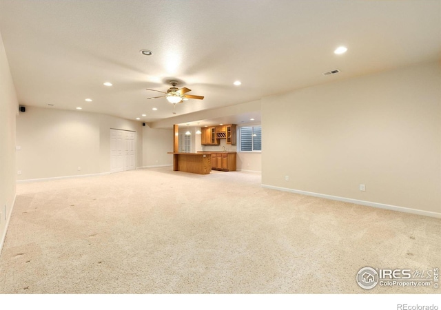 unfurnished living room featuring light carpet and ceiling fan