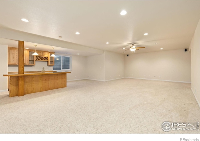 unfurnished living room featuring light carpet, wet bar, and ceiling fan