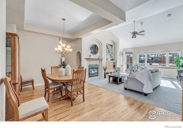 dining room featuring a tray ceiling, ceiling fan with notable chandelier, and light wood-type flooring