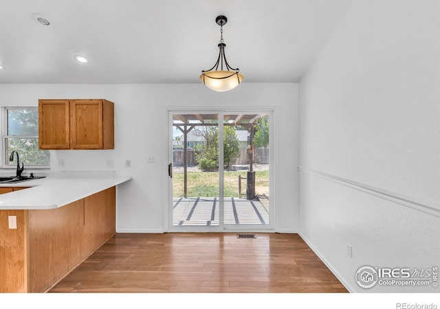 kitchen featuring sink, a breakfast bar area, hanging light fixtures, kitchen peninsula, and light wood-type flooring