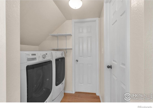 clothes washing area featuring washing machine and dryer and light hardwood / wood-style flooring