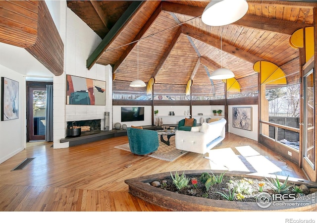 living room with hardwood / wood-style flooring, wooden ceiling, a large fireplace, and beamed ceiling