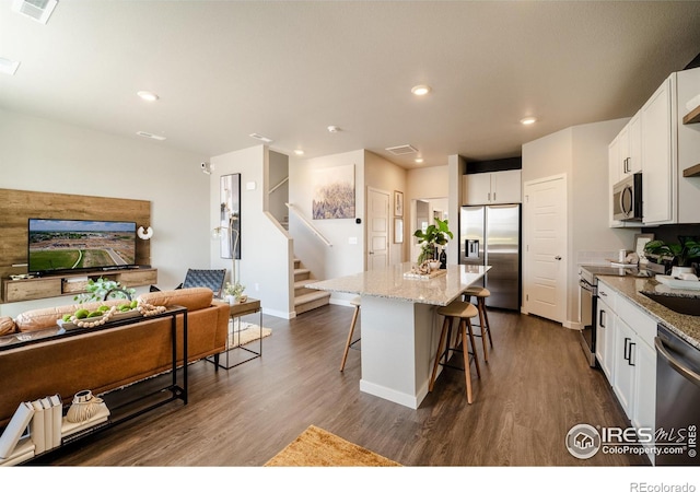 kitchen featuring white cabinetry, light stone counters, a kitchen breakfast bar, a kitchen island, and stainless steel appliances