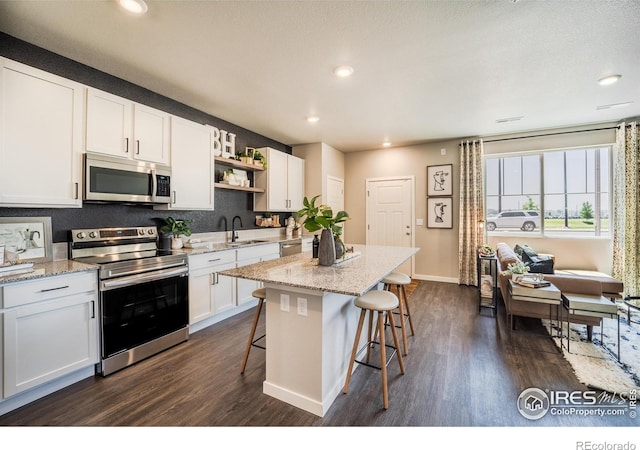 kitchen featuring sink, a center island, a kitchen breakfast bar, stainless steel appliances, and white cabinets