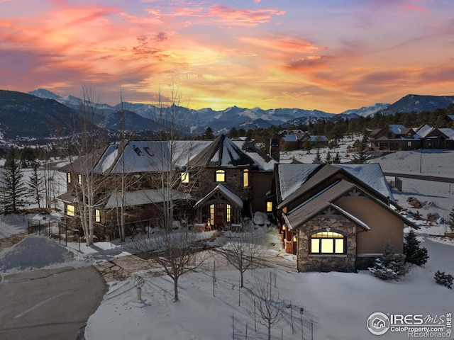 snow covered back of property featuring a mountain view