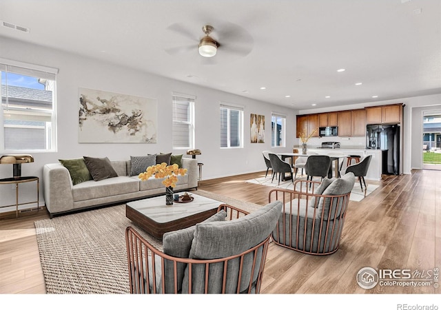 living room featuring ceiling fan and light hardwood / wood-style floors