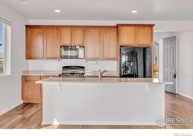 6508 Copper Dr, Frederick, CO 80516 - kitchen featuring black refrigerator with ice dispenser, gas stove, light countertops, light wood finished floors, and baseboards