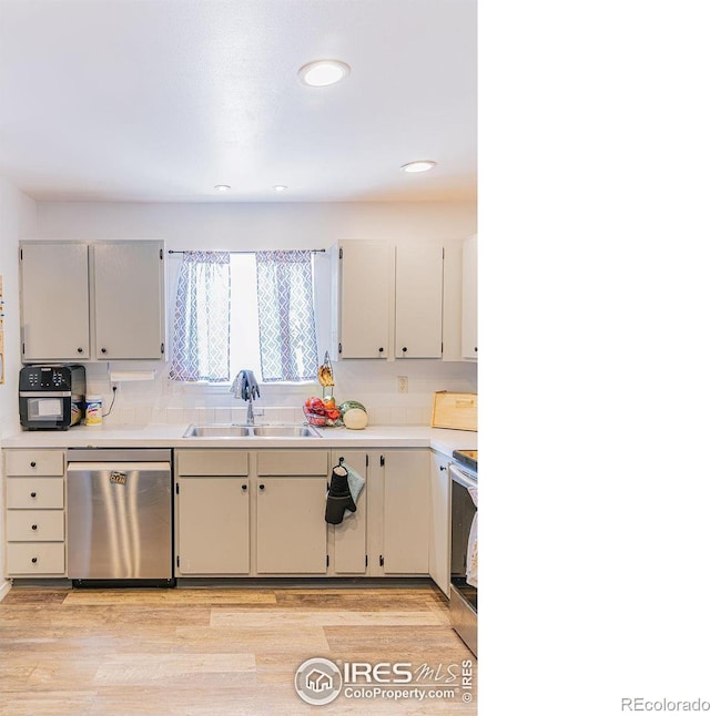 kitchen featuring appliances with stainless steel finishes, light hardwood / wood-style floors, sink, and decorative backsplash