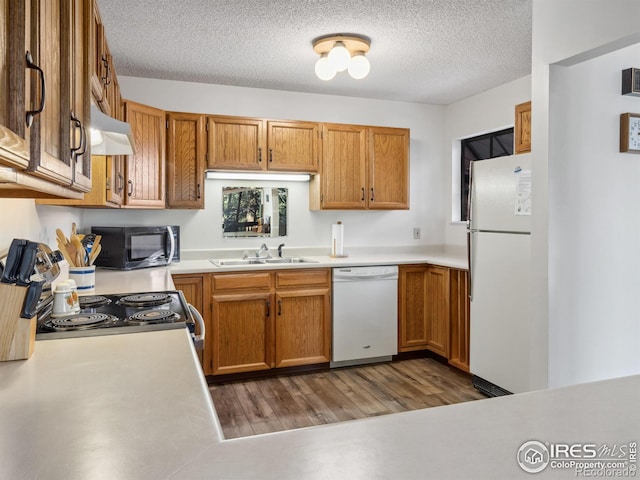 kitchen with sink, white appliances, hardwood / wood-style floors, extractor fan, and a textured ceiling