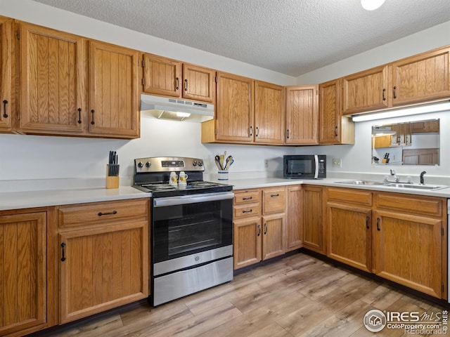 kitchen featuring sink, stainless steel range with electric cooktop, light hardwood / wood-style floors, and a textured ceiling