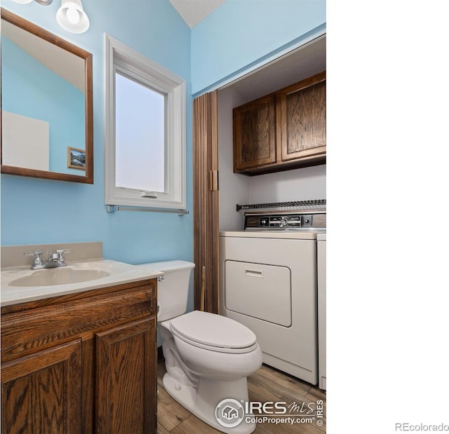 bathroom featuring vanity, washer / dryer, wood-type flooring, and toilet