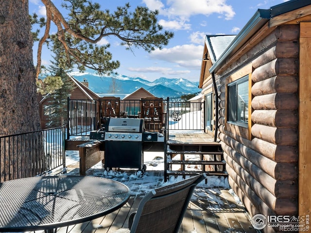 snow covered deck with a mountain view and grilling area