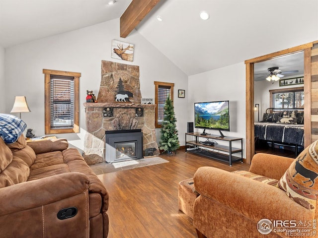 living room featuring hardwood / wood-style floors, high vaulted ceiling, a fireplace, beamed ceiling, and ceiling fan