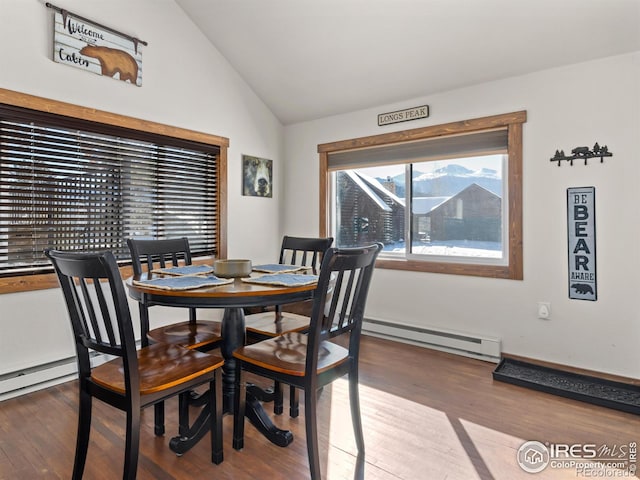 dining area featuring a baseboard heating unit, vaulted ceiling, and wood-type flooring