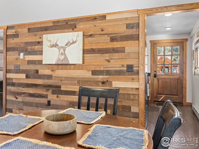 dining area featuring dark wood-type flooring and wooden walls