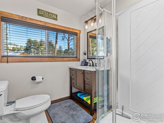 bathroom featuring vanity, toilet, and a shower with door