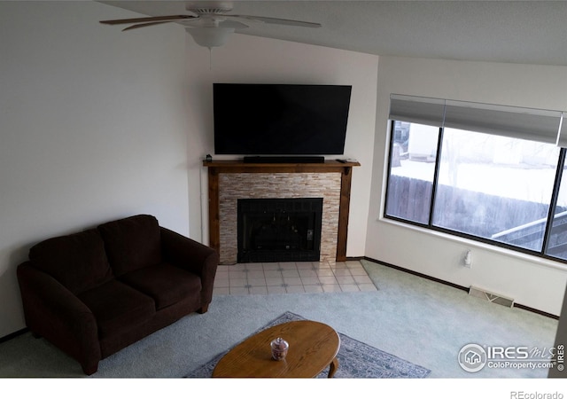 living room featuring a fireplace, light colored carpet, and ceiling fan