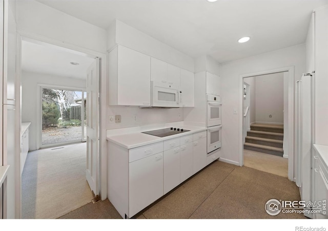 kitchen with light carpet, white cabinets, and white appliances