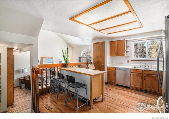 kitchen featuring appliances with stainless steel finishes, a kitchen bar, sink, and light hardwood / wood-style flooring