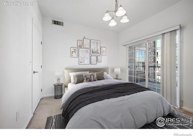 carpeted bedroom with an inviting chandelier and access to exterior