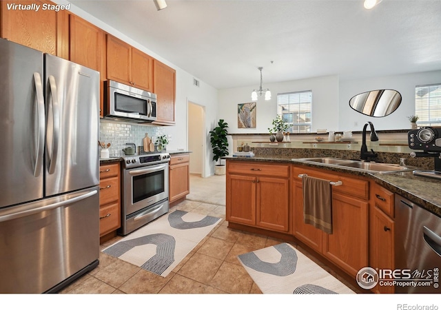 kitchen featuring appliances with stainless steel finishes, decorative light fixtures, tasteful backsplash, sink, and an inviting chandelier