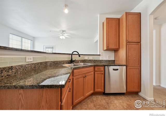 kitchen with sink, ceiling fan, dark stone countertops, fridge, and kitchen peninsula