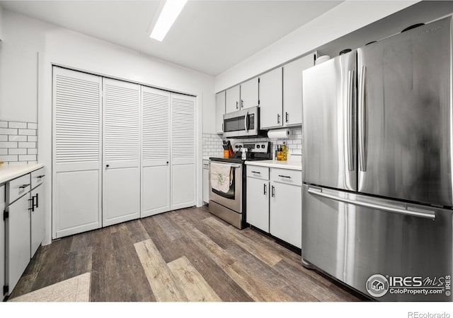 kitchen with stainless steel appliances, backsplash, white cabinets, and dark hardwood / wood-style flooring