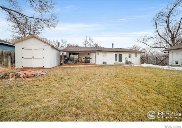 rear view of property with a yard, central AC, a storage unit, and a deck