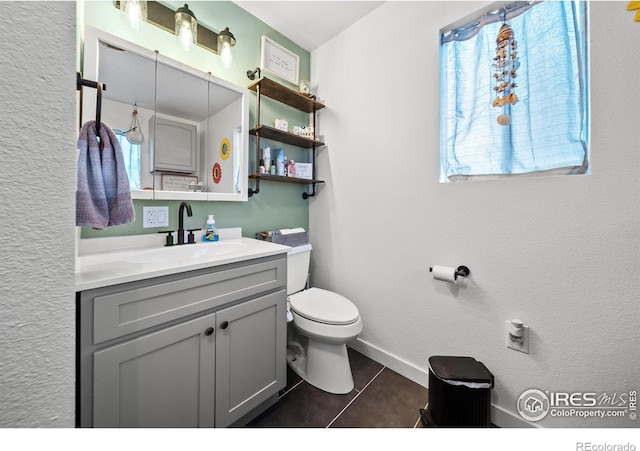 bathroom with vanity, tile patterned floors, toilet, and a healthy amount of sunlight