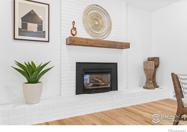 interior details with wood-type flooring and a brick fireplace