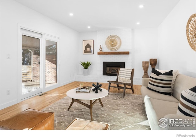 living room featuring hardwood / wood-style flooring and a brick fireplace