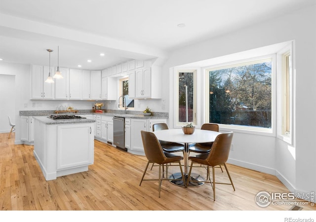 kitchen featuring appliances with stainless steel finishes, a center island, light hardwood / wood-style floors, white cabinets, and decorative light fixtures