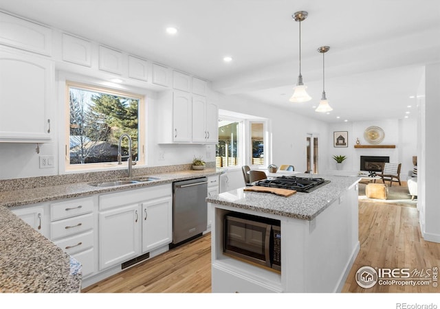 kitchen with appliances with stainless steel finishes, sink, white cabinets, and decorative light fixtures