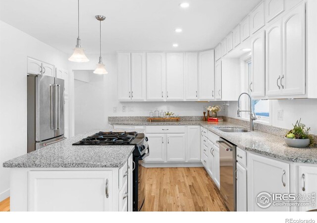 kitchen featuring sink, hanging light fixtures, a kitchen island, stainless steel appliances, and white cabinets