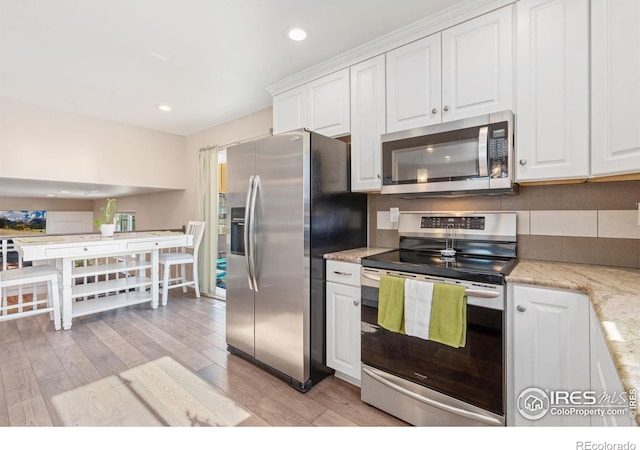 kitchen with light stone counters, stainless steel appliances, light hardwood / wood-style floors, and white cabinets