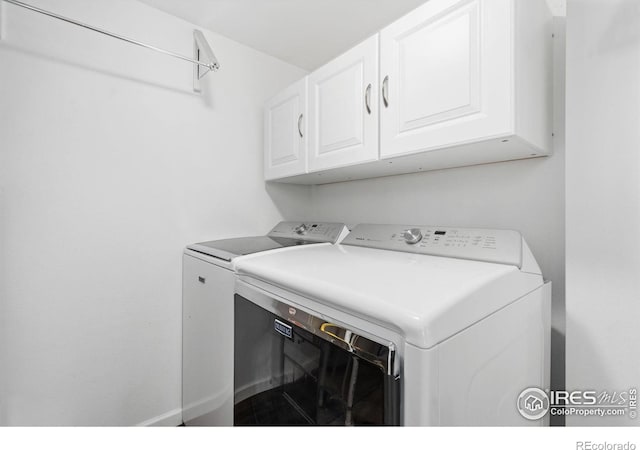 clothes washing area featuring cabinets and separate washer and dryer