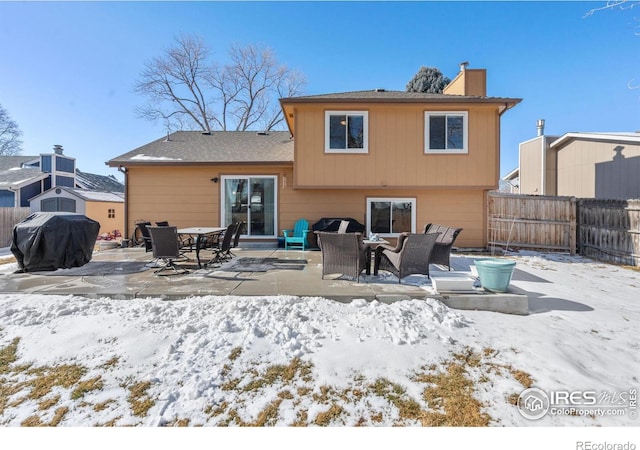 snow covered back of property featuring a patio area