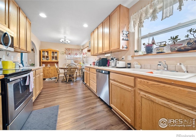 kitchen featuring sink, stainless steel appliances, a notable chandelier, light brown cabinetry, and light wood-type flooring