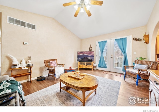 living room with lofted ceiling, french doors, ceiling fan, and light wood-type flooring