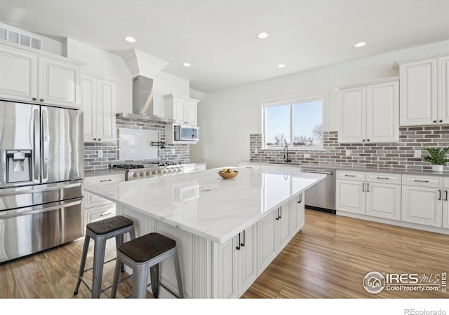 kitchen featuring a center island, light wood-type flooring, appliances with stainless steel finishes, light stone countertops, and white cabinets